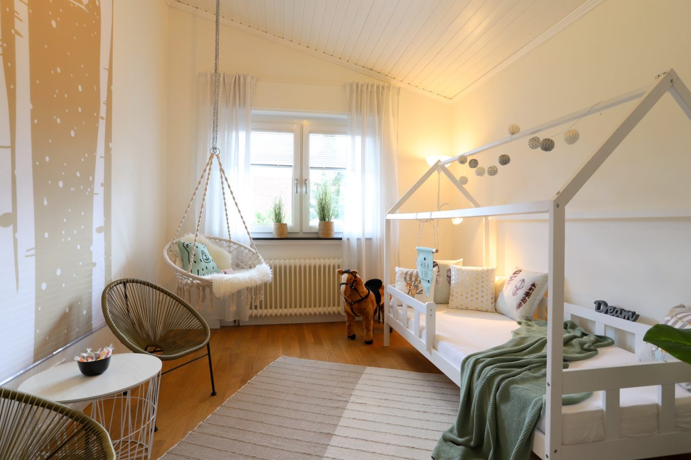 Immobilienamt Münster Helles, stilvolles Zimmer mit Hängesessel und modernem Bett. Grüne Akzente und Holzdetails.