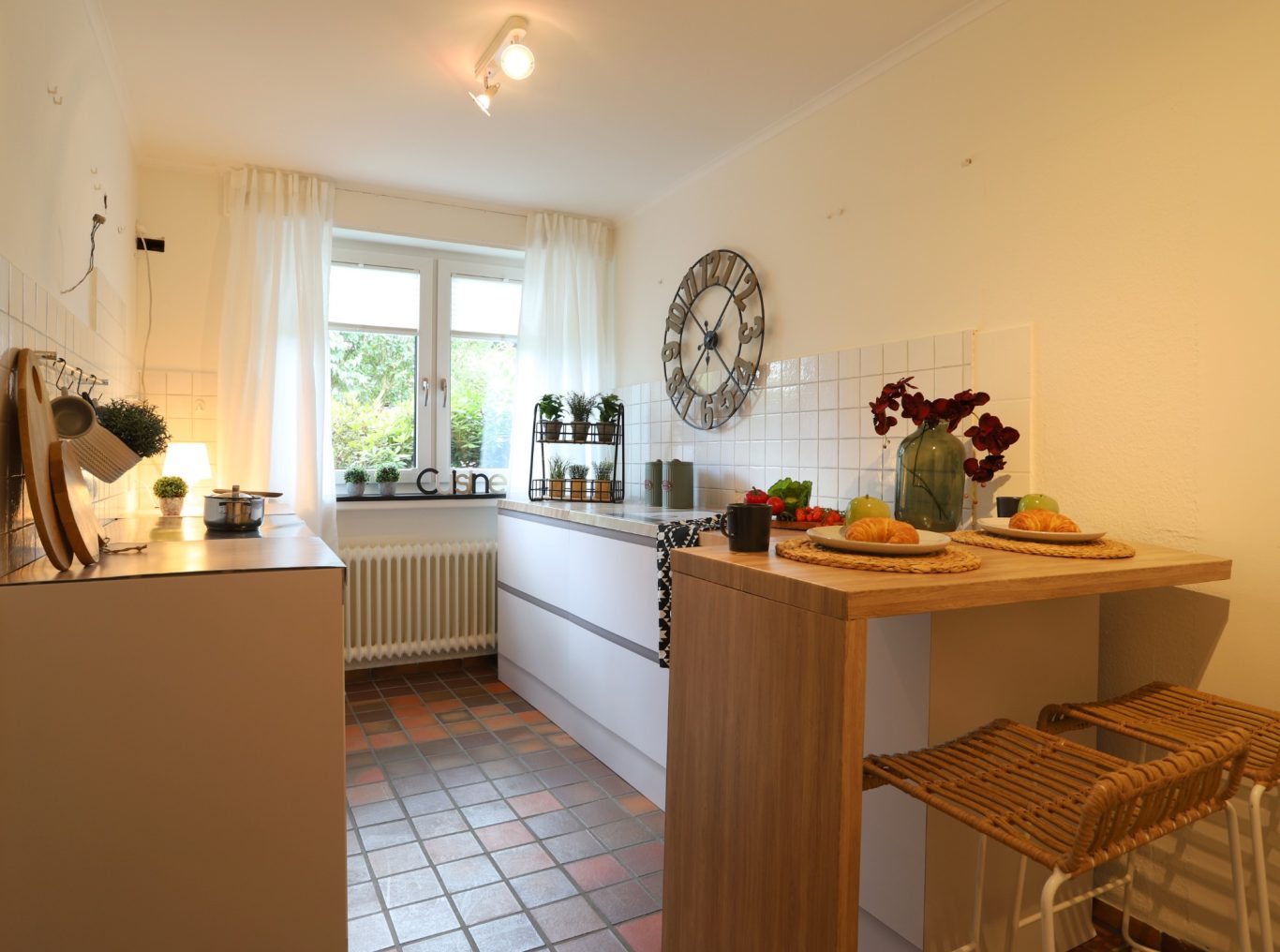 Hausverkauf Münster Helle, moderne Küche mit Holzdetails, kleiner Essbar und Pflanzen auf der Fensterbank.