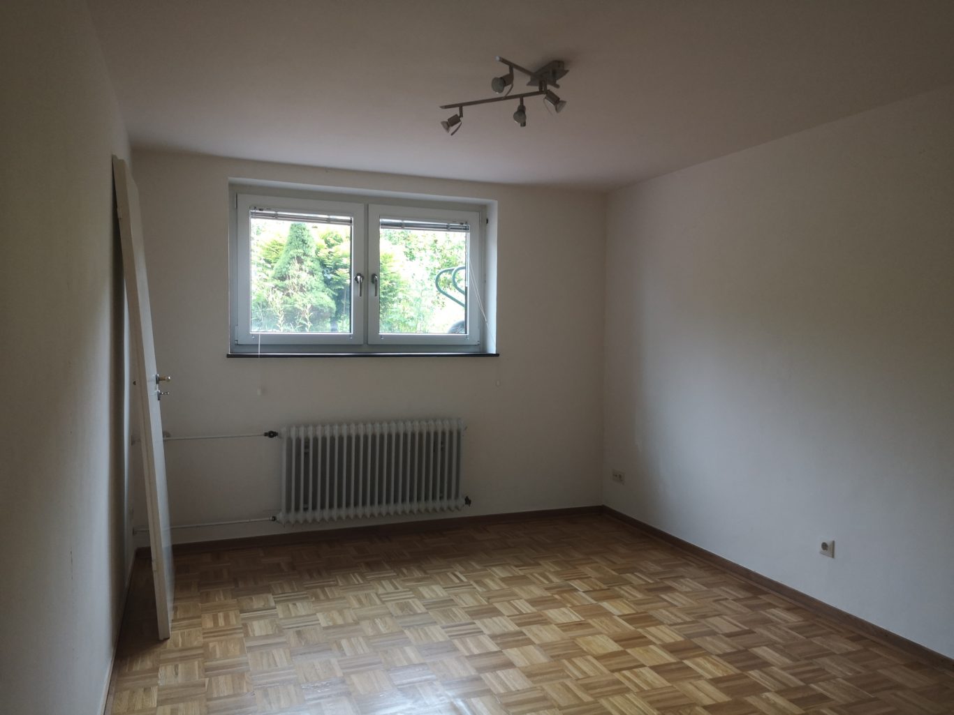 Preis Wohnung Münster Heller leerer Raum mit Parkettboden und Fenstern zur Natur.