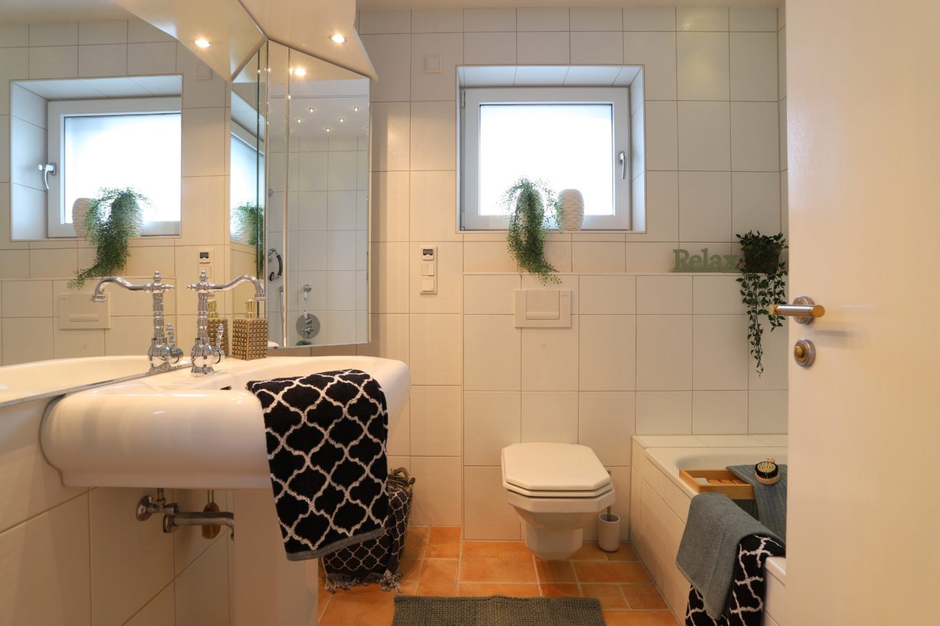 Immobilienmakler Helles Badezimmer mit Dusche, Badewanne, Waschbecken und modernen Fliesen.