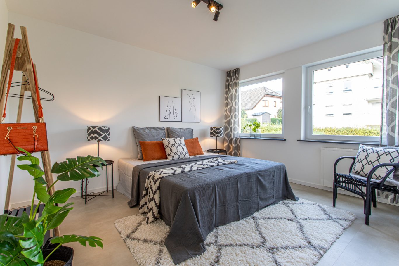 Immobilienmakler Münster Helles Schlafzimmer mit Doppelbett, Sessel und Pflanzen, in modernen Farben dekoriert.