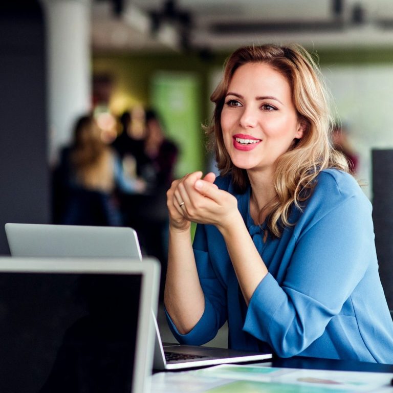 Immobilienmaklerin Münster Lächelnde Immobilienmaklerin in Münster, die während eines Gesprächs sitzt.