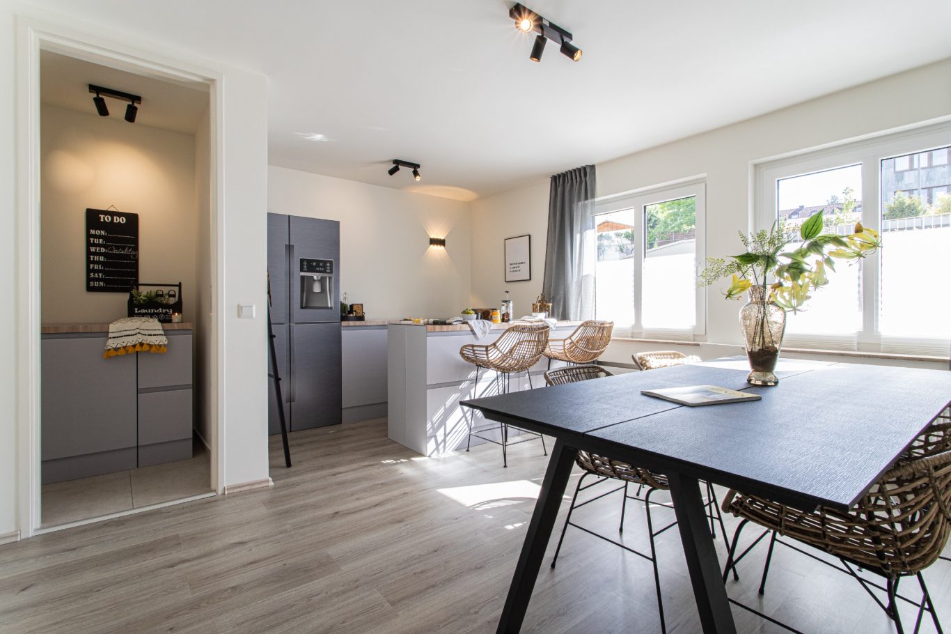 Immobilienmakler Münster Helles, modernes Wohn- und Esszimmer mit Küchenzeile und elegantem Tisch.